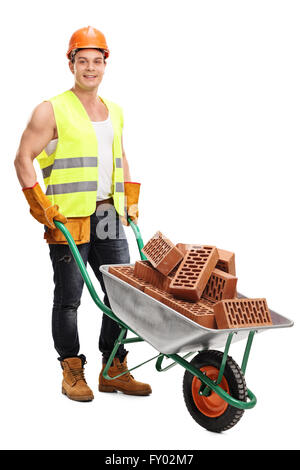 Full length portrait of a cheerful construction worker posing with a wheelbarrow full of bricks isolated on white background Stock Photo