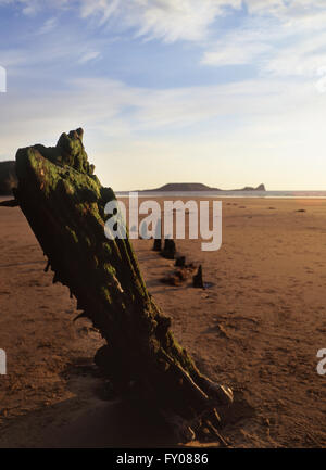 Helvetia shipwreck Rhossili beach view to Worm's Head at sunset Gower Peninsula South Wales UK Stock Photo