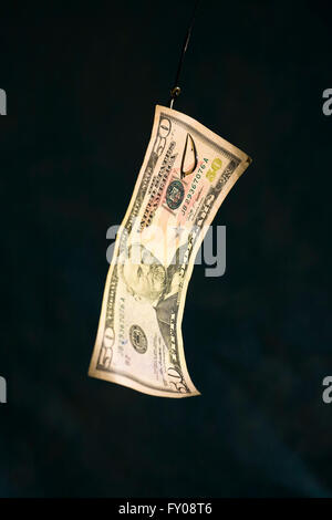 A Fifty Dollar Bill hangs suspended from a fishing hook Stock Photo