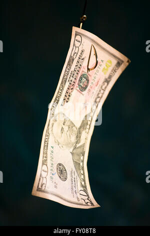 A Fifty Dollar Bill suspended as bait from a gold fish hook Stock Photo