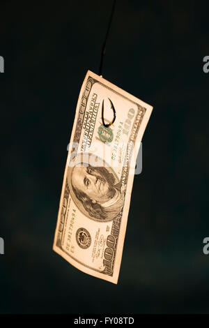 A 100 bill hanging on a fishing hook, focus on Benjamin Franklin's face Stock Photo