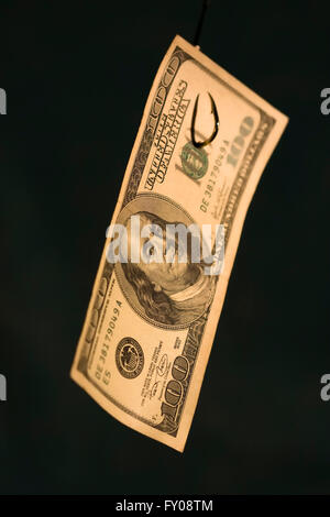 A 100 bill hanging on a fishing hook on a dark blue background with focus on Ben Franklin's face Stock Photo