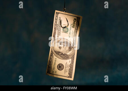 A 100 dollar bill hanging on a fishing hook on a light blue background Stock Photo