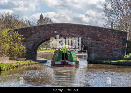 Canal narrowboat passes under an old brick bridge on The National Waterways Museum in Ellesmere Port, Cheshire, England, Stock Photo