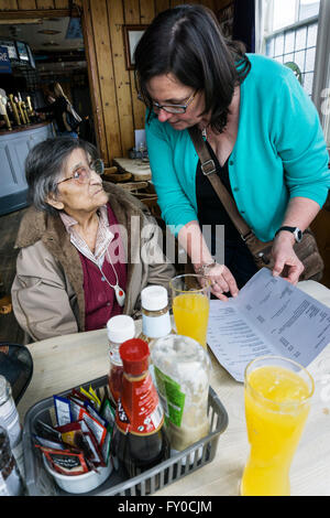 Ninety five year old woman taken out for a pub lunch by her daughter.  Choosing from the menu.  MODEL RELEASED. Stock Photo