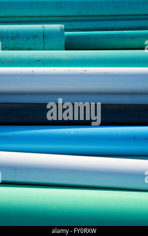 Abstract of blue, white and green water pipes stacked at a construction site on a sunny day Stock Photo