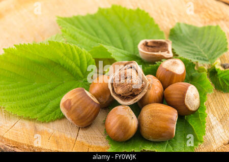 Raw hazelnuts on a green leaf placed on a wooden board Stock Photo