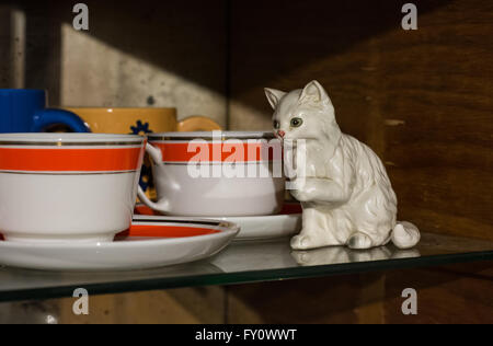 Cat figurine besides cups and plates Stock Photo