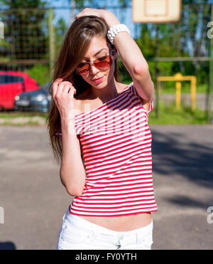 Beautiful young woman, outdoors, resting bright red T-shirt, fashion style, happy brunette hair straightening Stock Photo