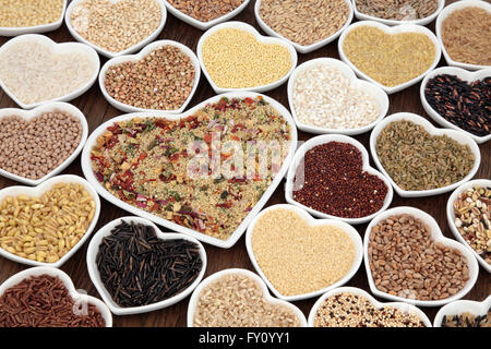 Large cereal and grain food selection in heart shaped porcelain bowls over lokta paper background. Stock Photo