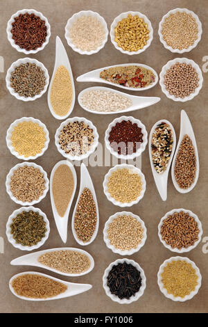 Large cereal and grain food selection in porcelain dishes over old brown paper background. Stock Photo