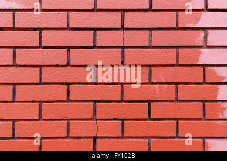 Texture of unevenly painted red brick wall with a vertical crack Stock Photo