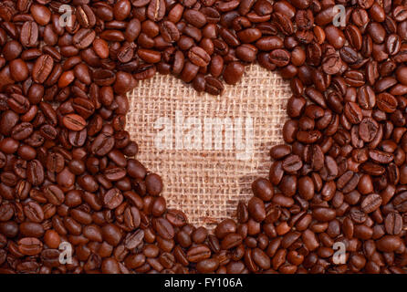 Roasted coffee beans with copy space in shape of a heart symbol for love of coffee on a burlap background Stock Photo
