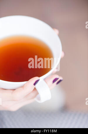 Close up of hands of woman holding a cup of tea. Concept of relaxation, taking a break and tranquility. Stock Photo