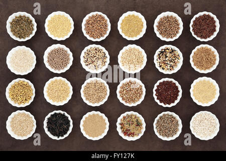 Large cereal and grain food selection in porcelain crinkle bowls over lokta paper background. Stock Photo
