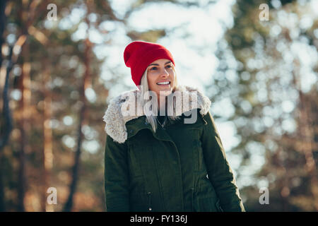 Low angle view of happy young woman wearing knit hat and jacket while looking away Stock Photo