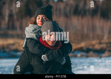 Portrait of happy man giving piggyback ride to woman during winter Stock Photo