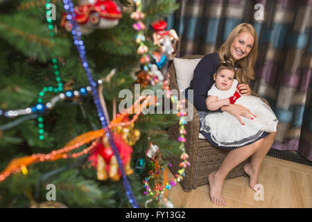 Portrait of happy mother sitting with baby girl celebrating Christmas Stock Photo