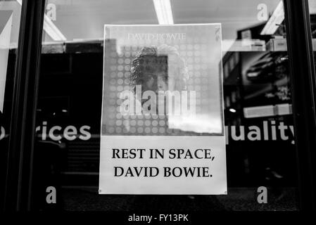 Poster tribute on a vinyl shop window with David Bowie portrait and the words 'Rest in space, David Bowie'.
