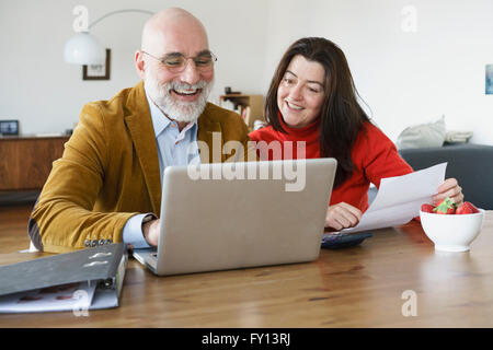 Happy mature couple using laptop on table at home Stock Photo