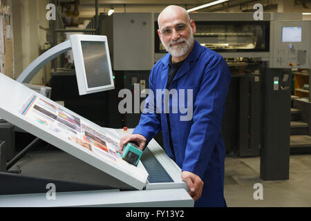 Portrait of smiling mature worker standing by equipment at printing press Stock Photo