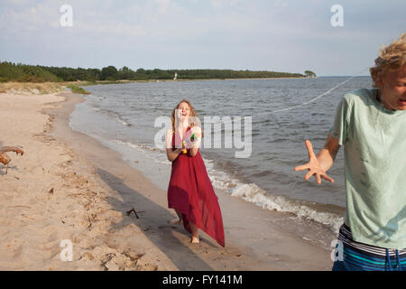 Woman spraying water on friend with squirt gun at beach Stock Photo