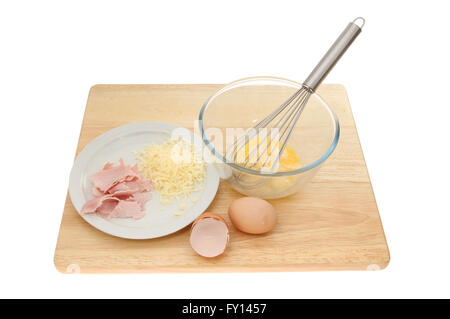 Cheese and ham omelette ingredients on a wooden chopping board isolated against white Stock Photo