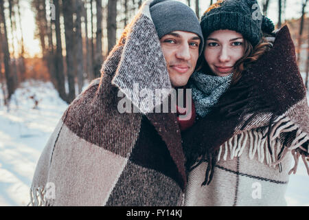 Portrait of smiling couple wrapped in blanket while standing on snow covered field Stock Photo