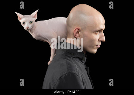 Profile view of bald man carrying Sphynx hairless cat on shoulder against black background Stock Photo
