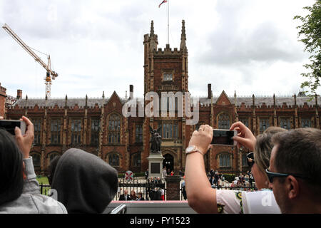 Tourists on Belfast tour bus taking photographs of The Queens University of Belfast and students on graduation day. Stock Photo