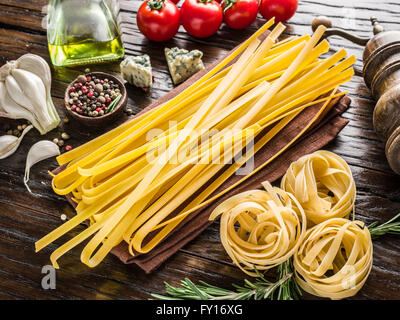 Pasta ingredients. Cherry-tomatoes, spaghetti pasta, rosemary and spices on the wooden table. Stock Photo