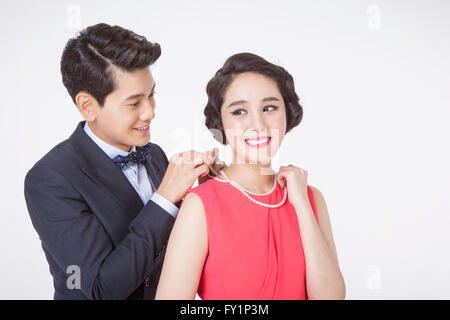 Portrait of young smiling man putting a necklace around young smiling woman's neck Stock Photo