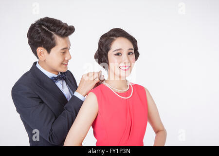 Portrait of young smiling man putting a necklace around young smiling woman's neck Stock Photo