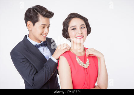 Portrait of young smiling man wearing putting a necklace around young smiling woman's neck Stock Photo