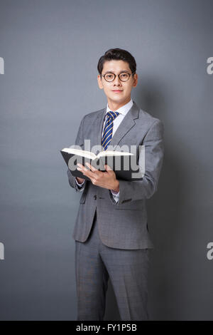 Young business man in gray suit standing with open book staring at front Stock Photo