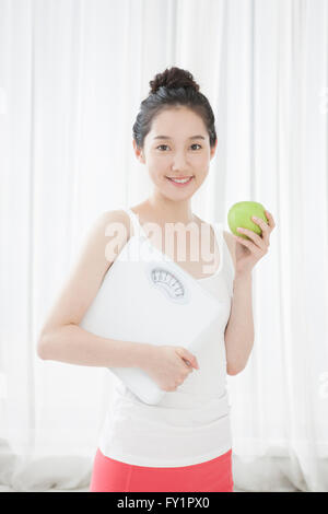Young smiling woman holding a scale and an apple Stock Photo