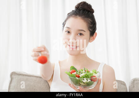 Portrait of young smiling woman eating salad Stock Photo