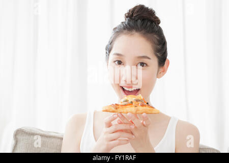 Portrait of young smiling woman eating pizza Stock Photo