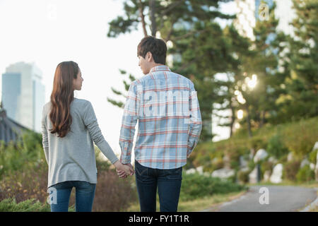 Back of young couple walking hand in hand at park Stock Photo