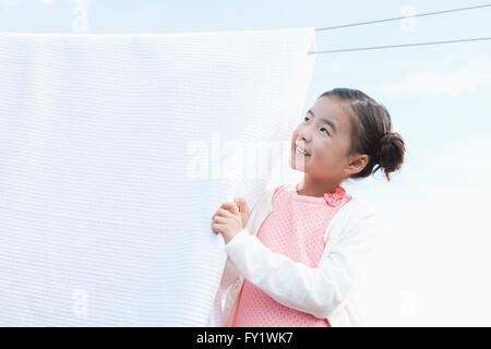 Girl holding a laundry hung out on a line and looking up Stock Photo