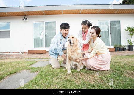 Family having fun with their dog at the yard of their house representing rural living Stock Photo