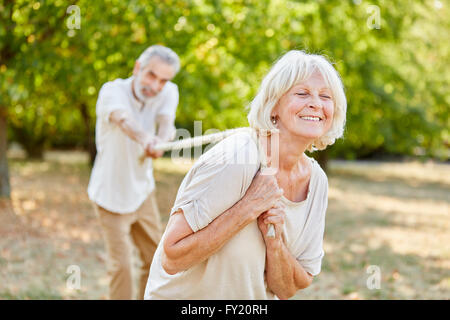 Two seniors playing tug of war with a rope in the nature Stock Photo