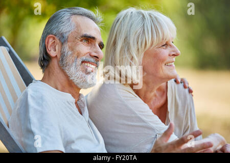 Happy senior couple in love sitting relaxed in summer in the nature Stock Photo