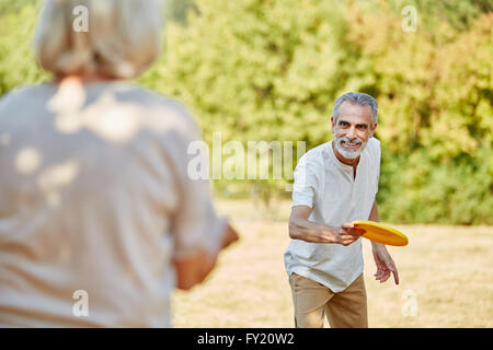 Active seniors playing with a frisbee in summer in the nature Stock Photo
