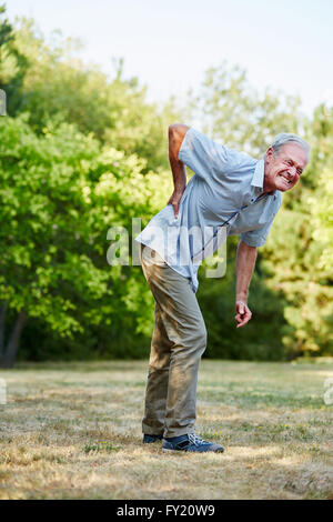 Old man having lumbago pain while walking in the park Stock Photo