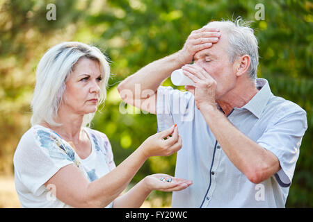 Senior woman gives headache pills to a man in the nature Stock Photo