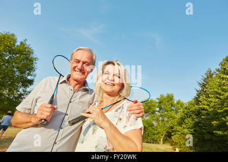 Happy senior couple playing badminton in summer in the nature Stock Photo