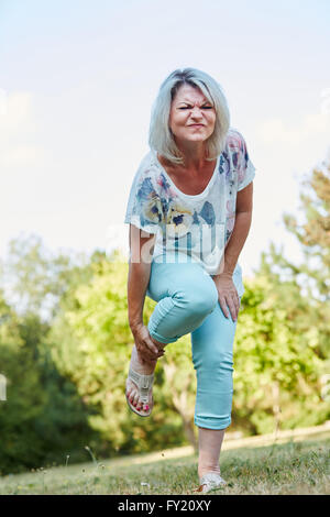 Old woman with sprained foot has pain in the nature Stock Photo