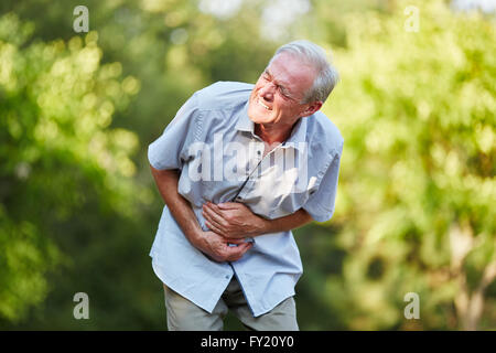Old man with stomach ache toching his stomach in the nature Stock Photo