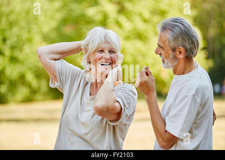 Old man gives a flower to senior smiling woman in the nature Stock Photo